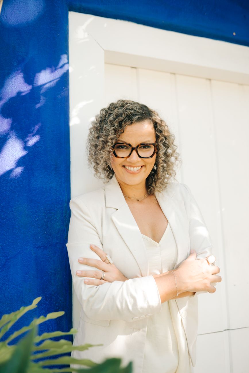 Naligia Duetti de braços cruzados, sorrindo, diante de uma porta azul